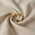 Anni – Gold Ring with Floral Motifs and Emerald Detail.